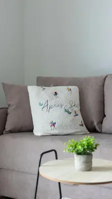 a pillow on a gray couch with a table at Lawa 22 in Kopaonik