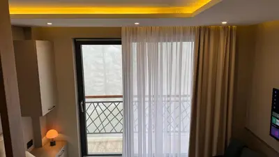 a room with a window with a curtain and a television at Pine apartments Residence Hill in Kopaonik