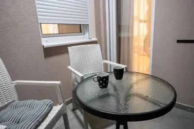 a glass table and chairs with two cups on it at 365stay in Vranje