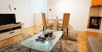 a living room with a table and chairs and a television at Apartment Eleven in Niš