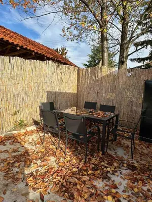 a table with chairs and a fence with leaves on the ground at Brick House