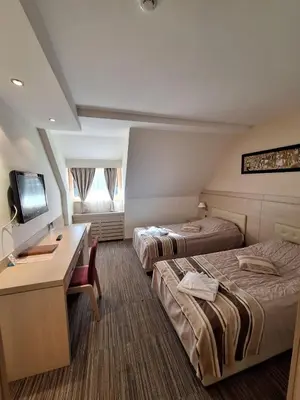 a hotel room with two beds and a desk at Angella Konaci KOPAONIK in Kopaonik