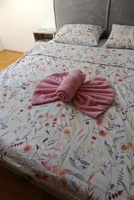 a bed with a blanket and two towels on it at Lux Studio River View in Niš