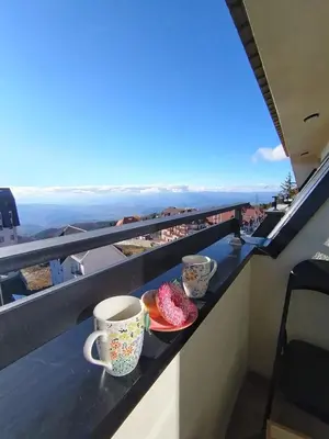 a table with cups and plates of food on a balcony at AlibiKopaonikSky32 in Kopaonik