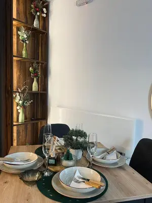 a wooden table with plates and wine glasses on it at Apartman Nina in Kopaonik