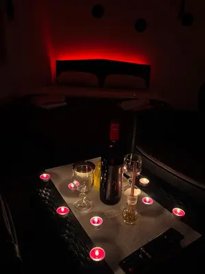a bottle of wine and glasses on a table in a dark room at Avram019 in Zaječar
