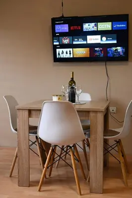 a dining room table with a white chair and a tv at River apartman Paraćin in Paraćin