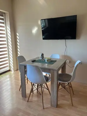a dining room table with chairs and a television on a wall at River apartman Paraćin in Paraćin