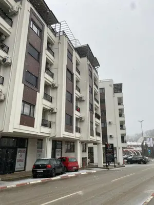 a building with two cars parked in front of it at Apartman Adamović in Vrnjačka Banja