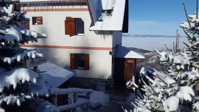 a house in the snow with trees in the foreground at Apartments Casa Pavlovic in Kopaonik