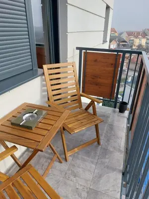 a wooden chair and a table on a balcony at Jagodina studio CRNJANSKI zatvoreni bazen in Jagodina