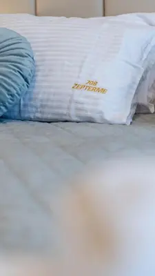 a white bed with a pillow on top of it at Zepterme Harmony in Vrnjačka Banja