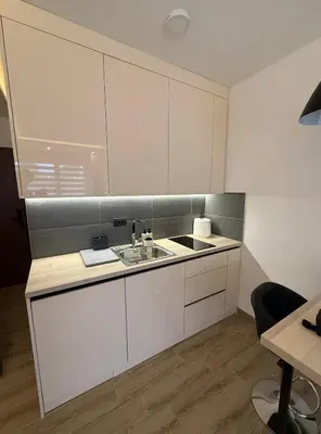 a kitchen with white cabinets and a sink at Apartman SEVN in Kopaonik