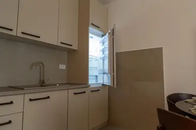 a kitchen with white cabinets and a sink and a window at Planet Gemini Residence & SPA in Niš