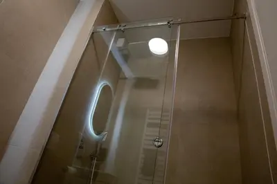 a shower with a glass door in a bathroom at Planet Gemini Residence & SPA in Niš