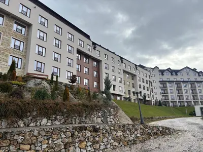 a large building with a stone wall in front of it at Apartman PETKOVIĆ NLux 110 Milmari resort in Kopaonik