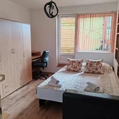 a bedroom with a bed with a desk and a window at Merak stan na dan in Vranje