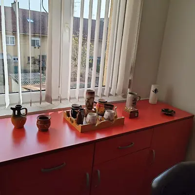 a red dresser with various items on it in front of a window at Merak stan na dan in Vranje