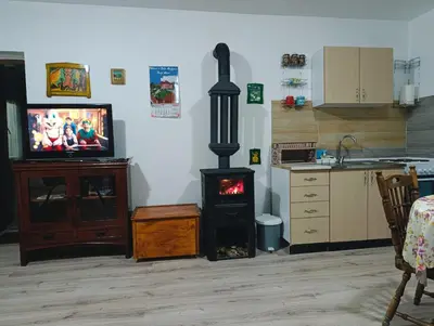 a living room with a stove with a tv and a kitchen at Oaza Mira Mozgovo in Mozgovo