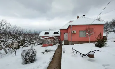 a red house with snow on the ground at Oaza Mira Mozgovo in Mozgovo