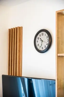 a clock on a wall next to a tv at La Casa in Vrnjačka Banja