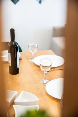 a bottle of wine sitting on a wooden table with glasses at La Casa in Vrnjačka Banja