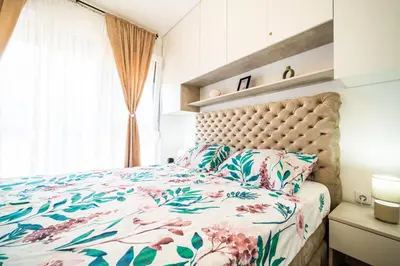 a bedroom with a bed with a floral bedspread and a window at La Casa in Vrnjačka Banja