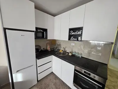 a small kitchen with white cabinets and a refrigerator at Apartman Bibi centar in Niš
