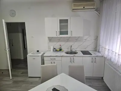 a white kitchen with a sink and a table at City Comfort Suite in Paraćin