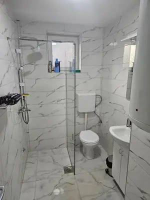 a bathroom with a toilet and a glass shower at City Comfort Suite in Paraćin