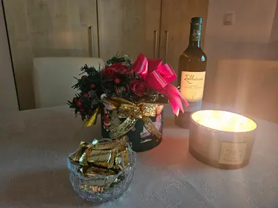 a candle and a bottle of wine and a vase with flowers at Apartman Vila Mir in Vrnjačka Banja