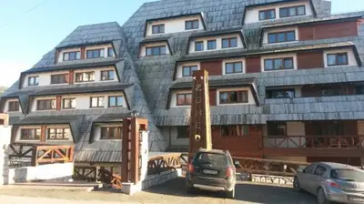 a large building with cars parked in front of it at Ski & Relax Apartment in Kopaonik