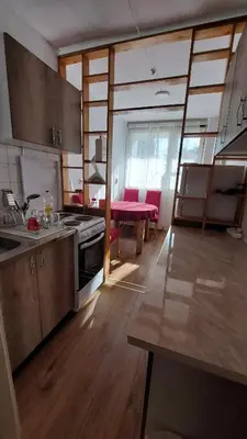 a kitchen with wooden floors and a kitchen with a table at Stan Na Dan Ćuprija in Ćuprija
