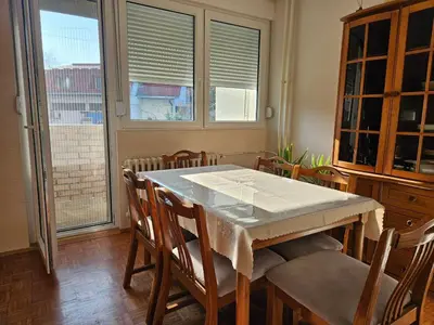 a dining room with a table and chairs and windows at DiO in Kruševac