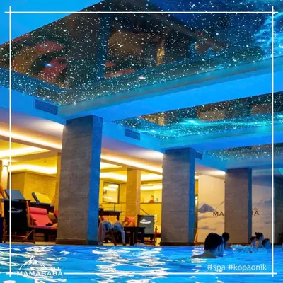 a woman in a swimming pool at night at Pleasure LUX G999 Kopaonik in Kopaonik