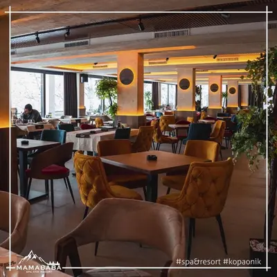 a restaurant with tables and chairs and people in the background at Pleasure LUX G999 Kopaonik in Kopaonik
