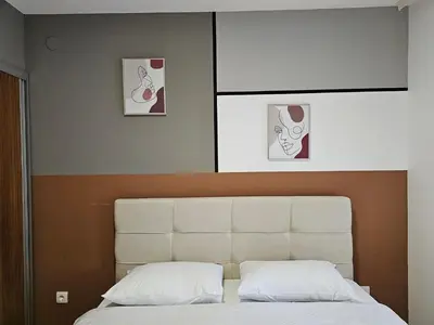 a bedroom with a white bed with three pictures on the wall at DeLux apartman Eleni rooms in Vrnjačka Banja