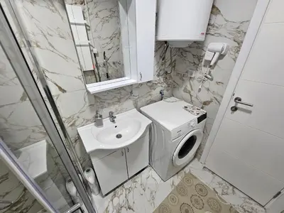a bathroom with a sink and a washing machine at DeLux apartman Eleni rooms in Vrnjačka Banja