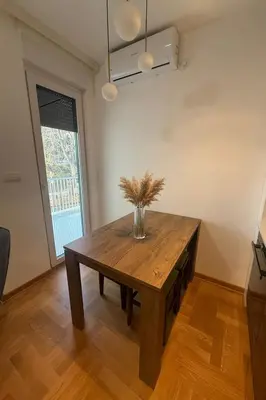 a dining room table with a vase of flowers on it at Soft Living Family Suite A6 in Vrnjačka Banja