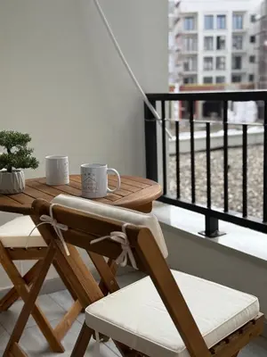 a table and chairs on a balcony with two cups at Apartman Banjac in Vrnjačka Banja