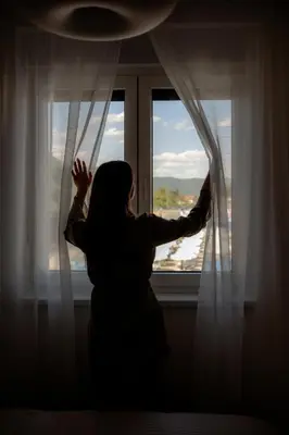 a woman is looking out of a window at LALA & DAUGHTERS Apartment in Vrnjačka Banja