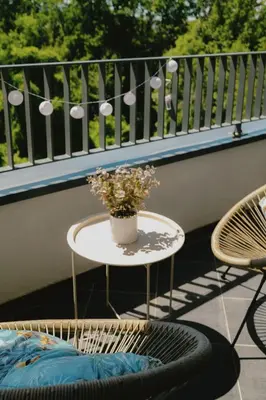 a table on a balcony with a vase of flowers at LALA & DAUGHTERS Apartment in Vrnjačka Banja
