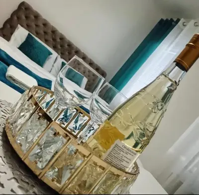 a glass table with two glasses and a bottle on it at Green place in Jagodina
