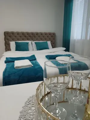two wine glasses on a table in front of a bed at Green place in Jagodina