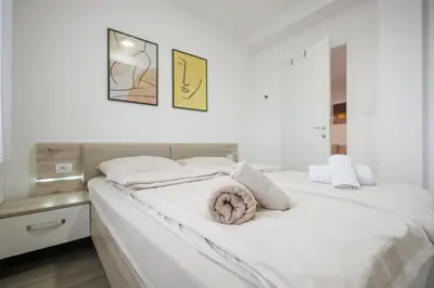 a white bedroom with a large bed with white sheets at Pirot LUX 1 in Pirot