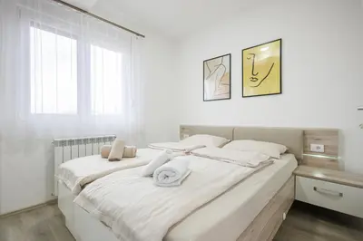 a white bedroom with a large bed with white sheets at Pirot LUX 1 in Pirot