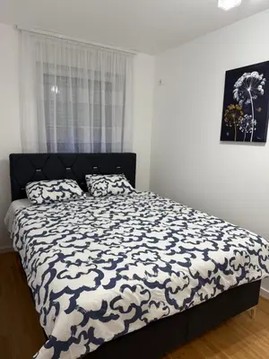 a bedroom with a bed with a black and white comforter at Apartment Sunny in Niš