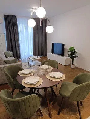 a living room with a dining table and chairs at Planet Green Residence in Niš