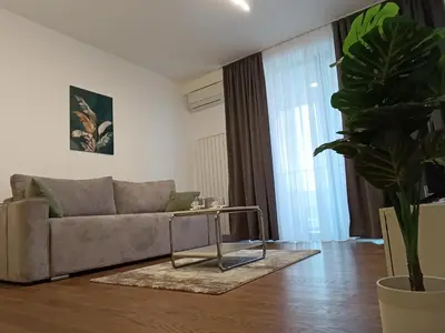 a living room with a couch and a potted plant at Planet Green Residence in Niš