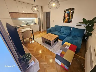 a living room with a blue couch and a table at Blue Wave Vrnjacka banja in Vrnjačka Banja